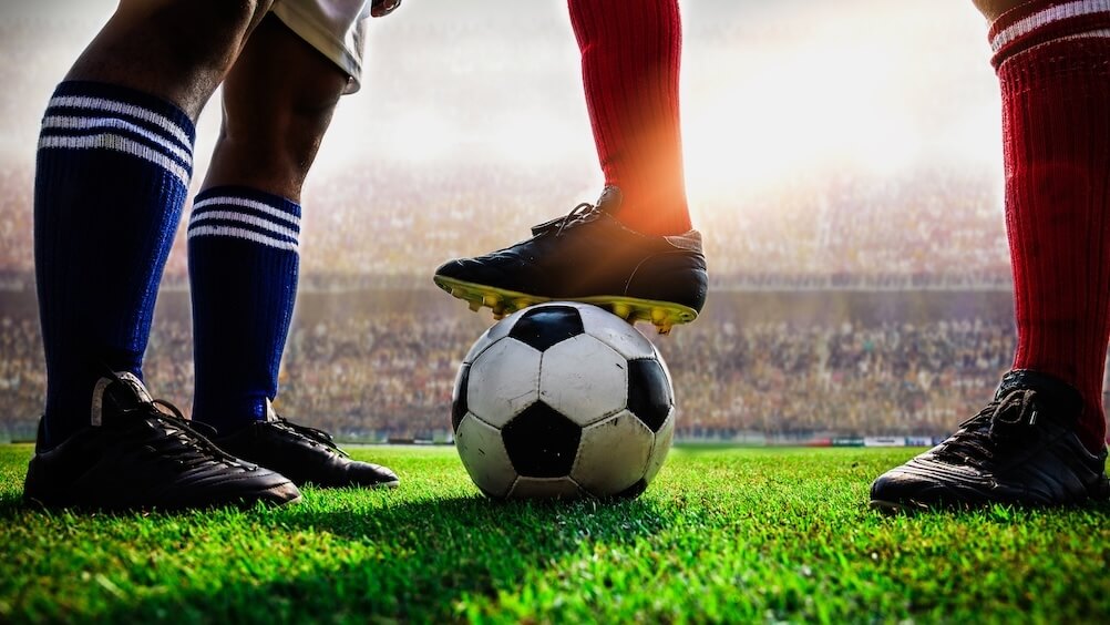 An image of the legs of two footballers on opposite teams, one with the ball beneath his foot. An equal match up is a good time to use draw no bet